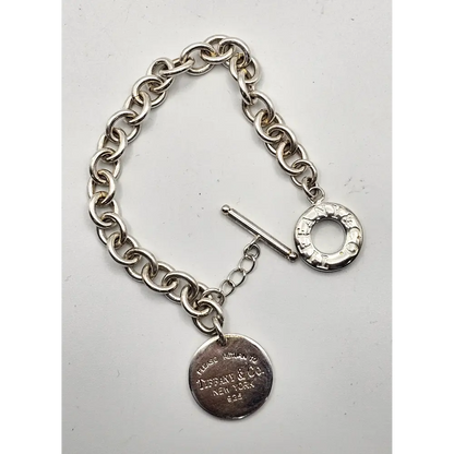Silver bracelet with a tag on a light gray 