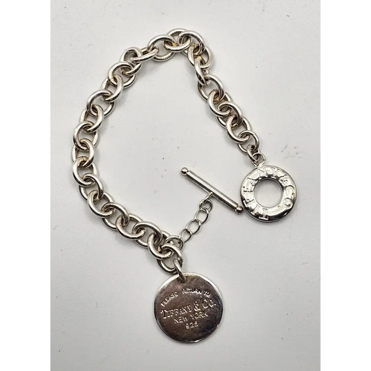 Silver bracelet with a tag on a light gray 