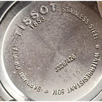 Close-up of Tissot watch caseback with branding and model details.