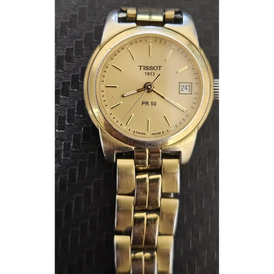 Gold Tissot watch on a textured black background