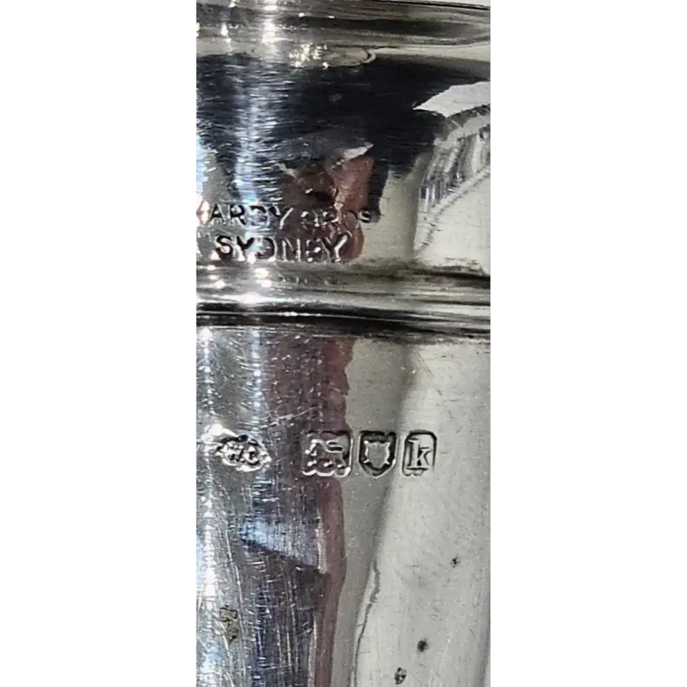 Close-up of a silver object with visible hallmarks on a white background