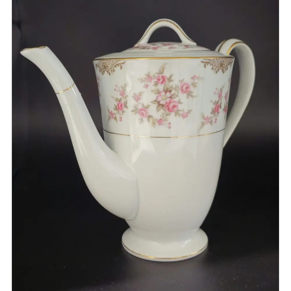 White teapot with floral design on a black background