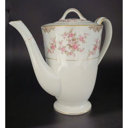 White teapot with floral design on a black background