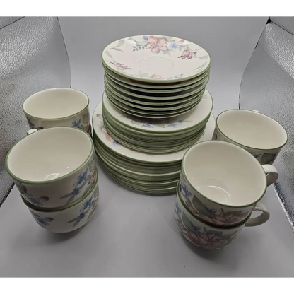 Set of ceramic plates and cups with floral design on a gray surface