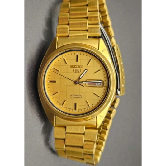 Gold Seiko watch on a gray background