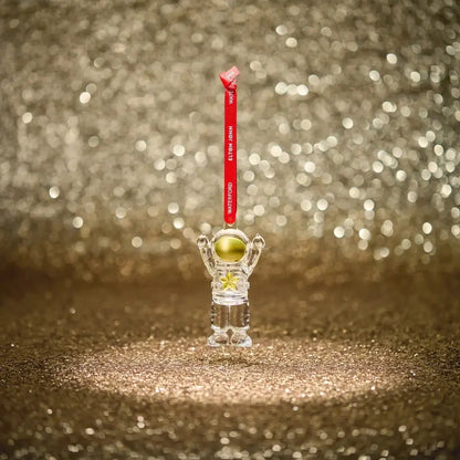 Clear astronaut figurine with a gold helmet on a red string 
