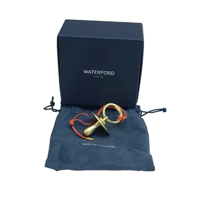 Gold and red object on a Waterford branded pouch with a Waterford box in the background.