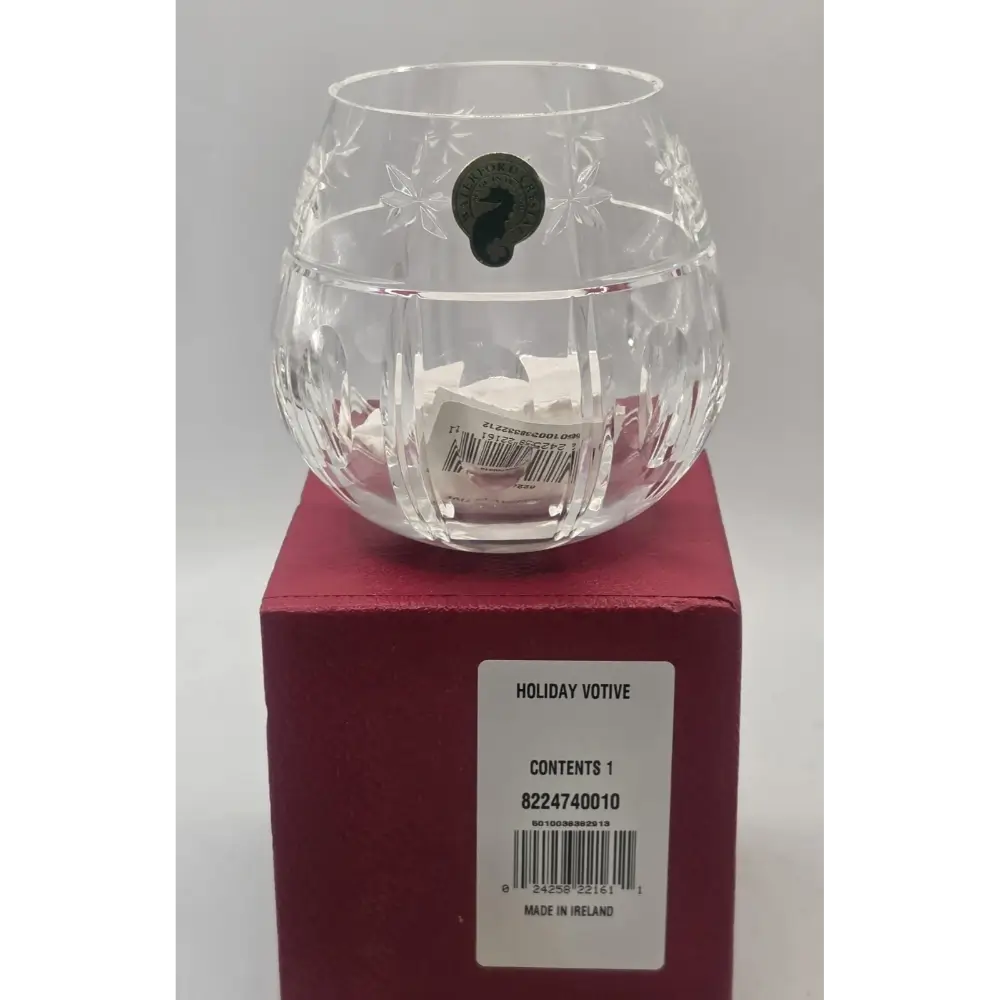 Clear glass votive candle holder on a red box with a label