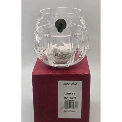 Clear glass votive candle holder on a red box with a label