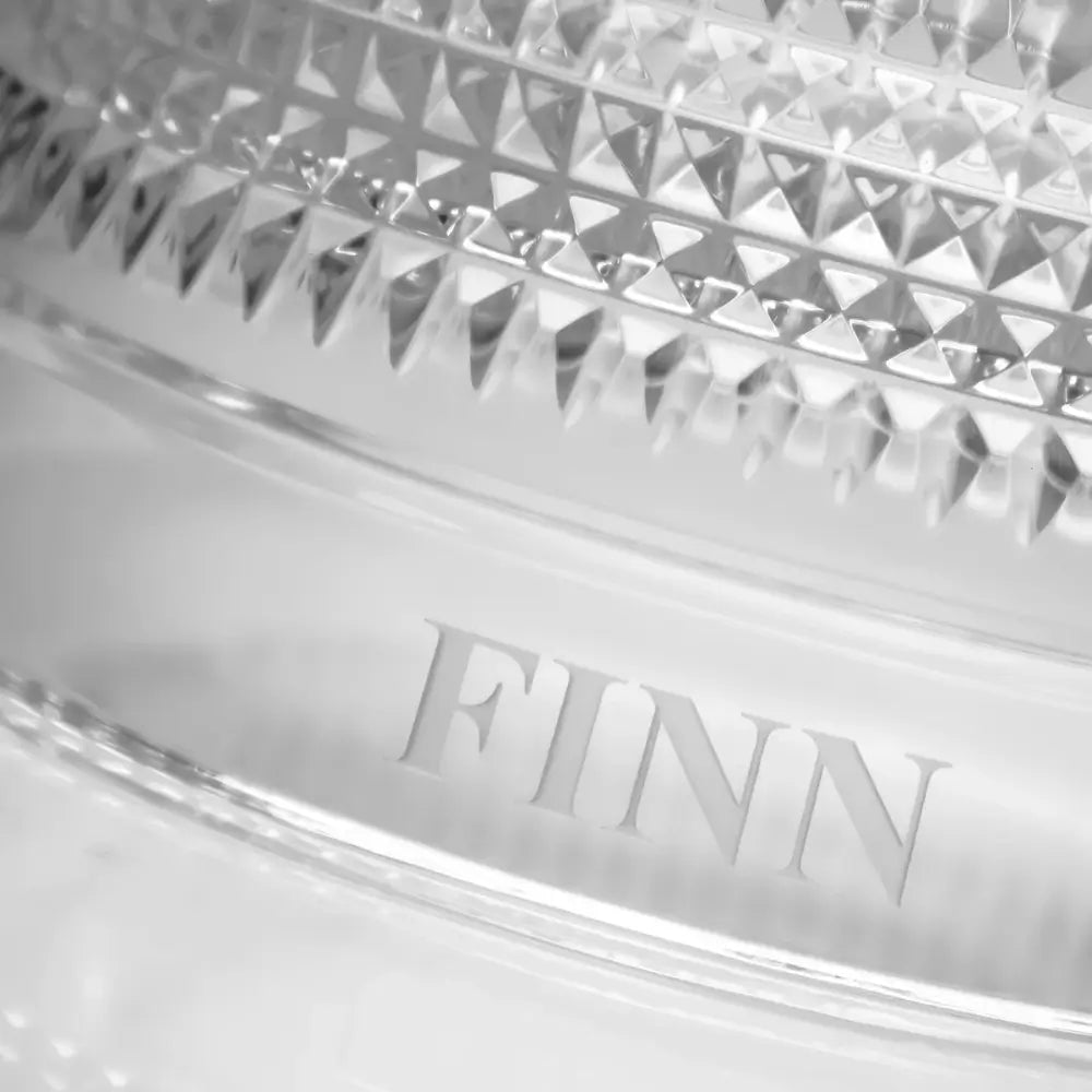 Close-up of a crystal dish with 'FINN' branding on a white background