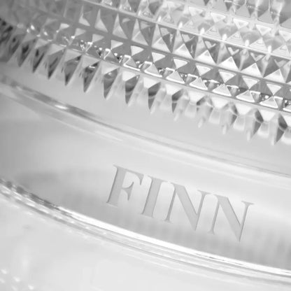 Close-up of a crystal dish with 'FINN' branding on a white background