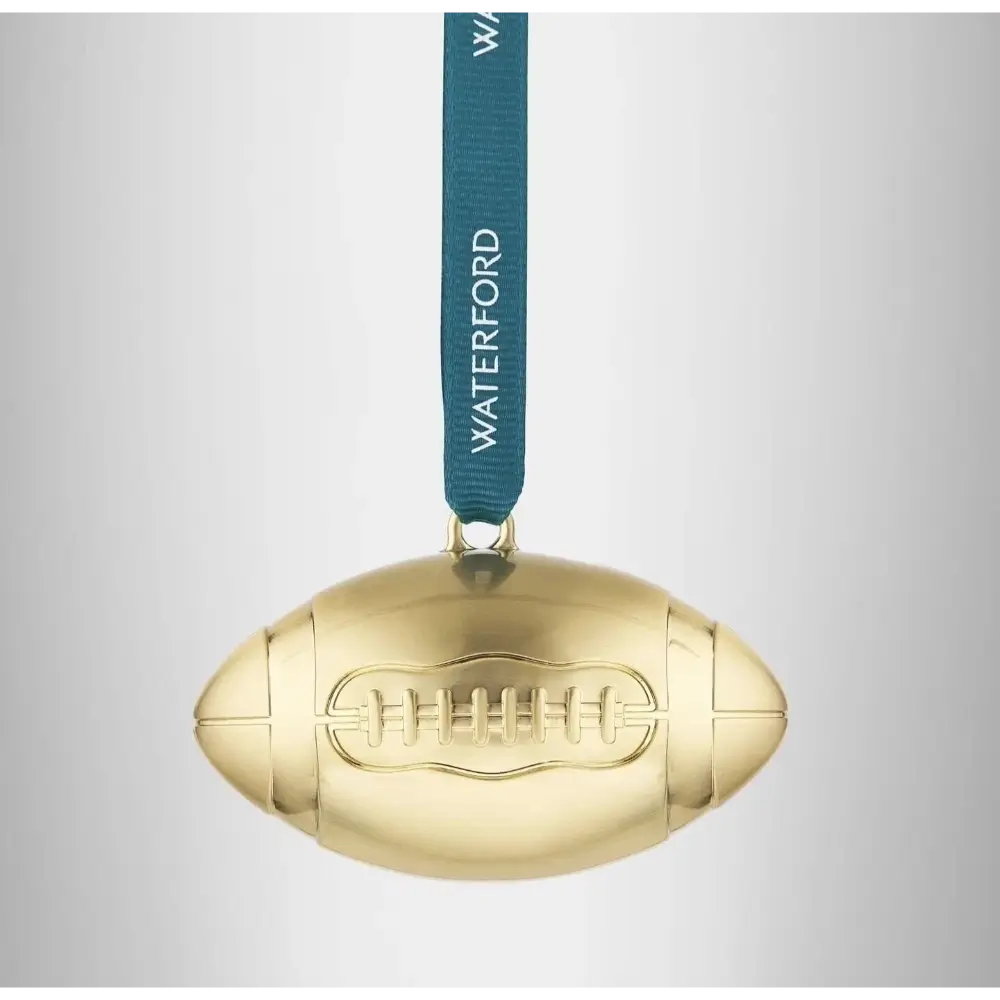 Gold football-shaped ornament with a blue ribbon and 'Waterford' text on a light gray background