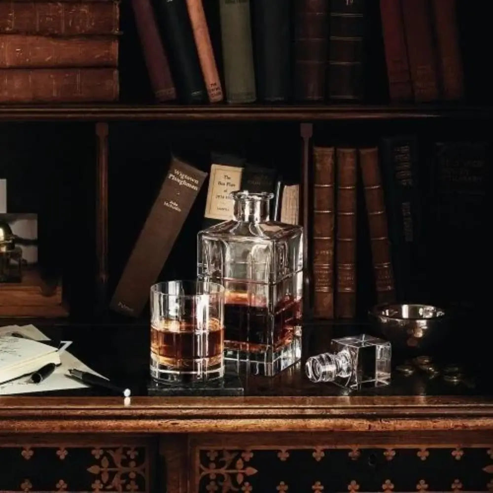 Glass decanter and glass with liquid on a wooden surface with books