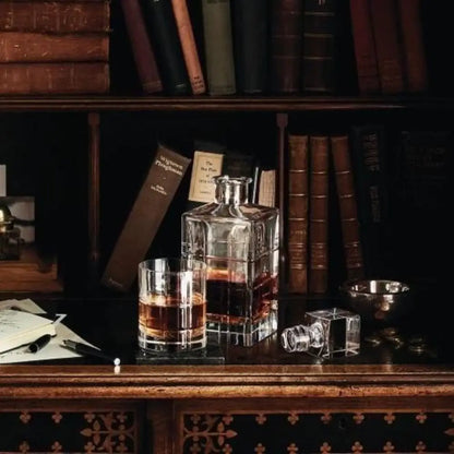 Glass decanter and glass with liquid on a wooden surface with books