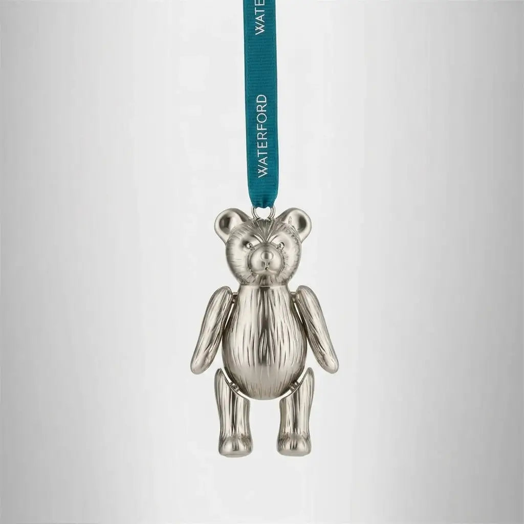 Silver teddy bear ornament with a green ribbon on a light gray background