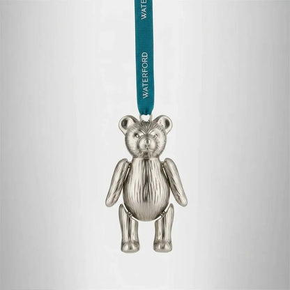 Silver teddy bear ornament with a green ribbon on a light gray background