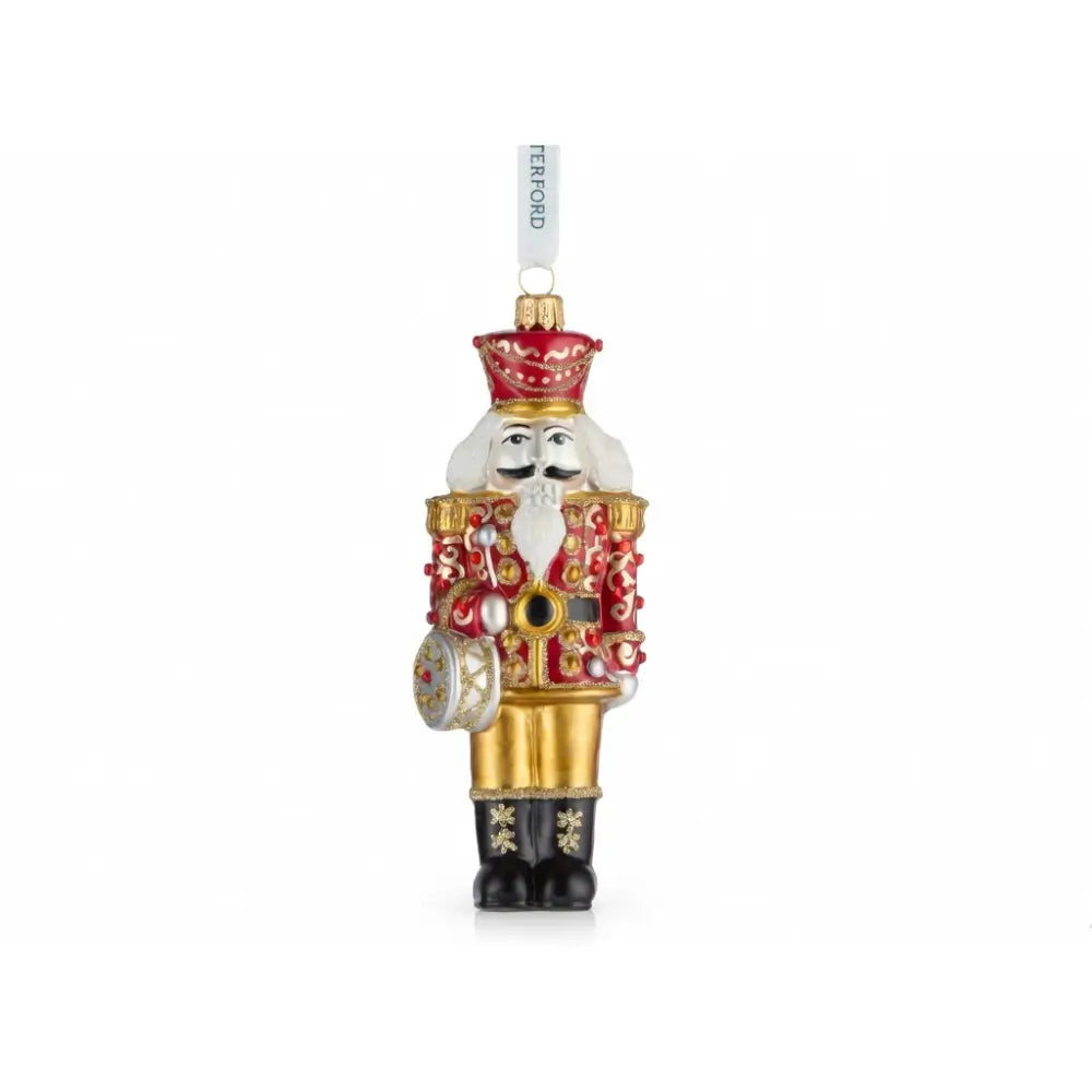 Decorative Christmas ornament resembling a nutcracker with gold and red details on a white background.