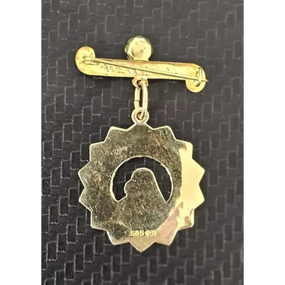 Gold brooch with a circular design on a textured black background