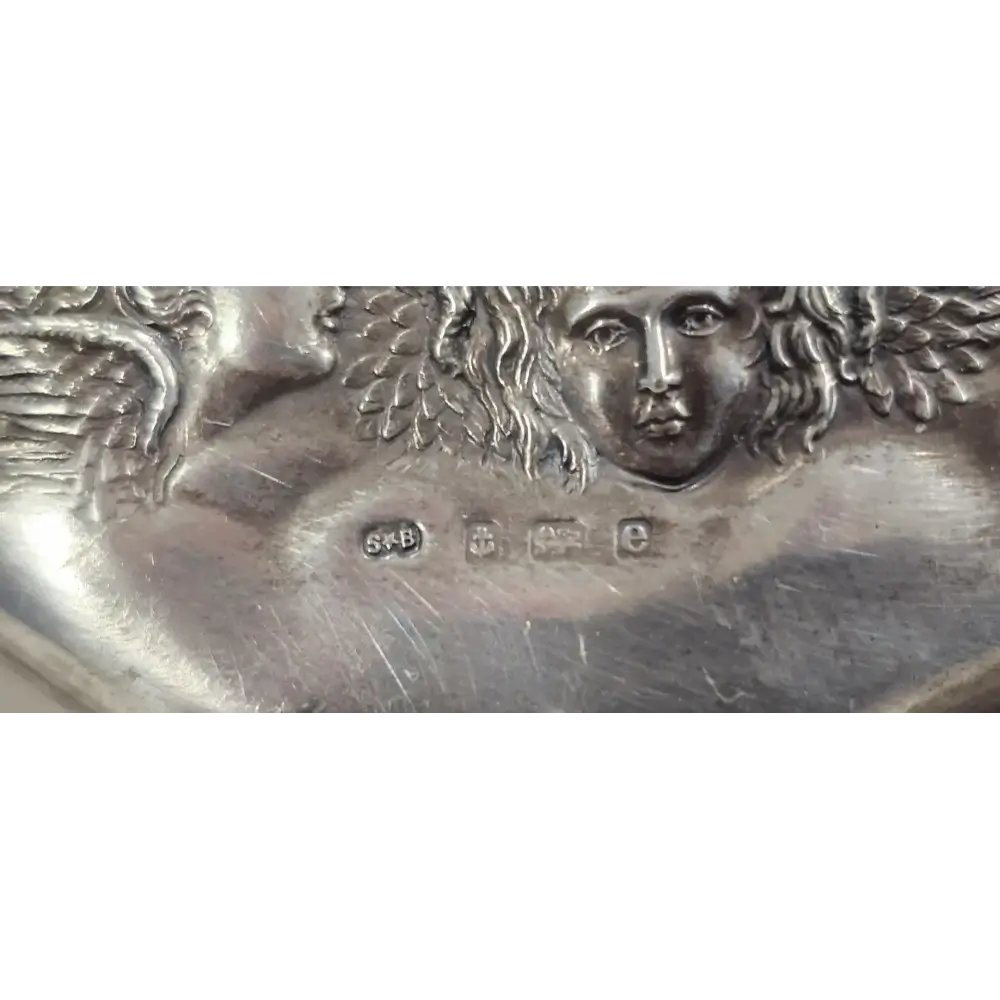 Close-up of a silver plaque with an angelic figure and engraved details
