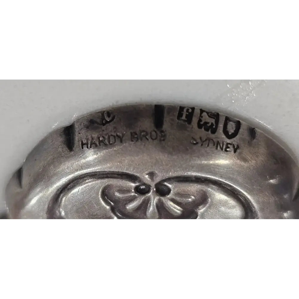 Close-up of a silver object with 'Hardy Bros Sydney' engraving