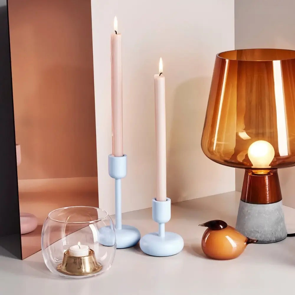 Decorative items including a lamp, candles, and a small bird-shaped object on a neutral background.