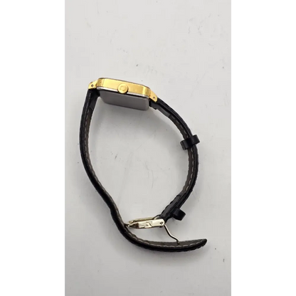 Gold watch with black leather strap on a gray background