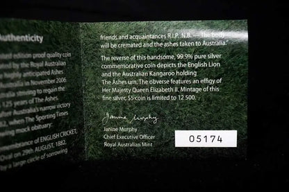 A close-up of a dark green Australian commemorative coin authenticity card with printed text, a signature, and a white label reading 05174 on a black background.