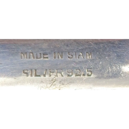 Metallic object with 'MADE IN SIAM' and 'SILVER 925' stamp on a white background