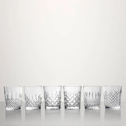 Six clear cut-crystal tumblers with different diamond and geometric patterns, lined up in a row on a reflective white surface against a light gray background from our Waterford Crystal Australia – Outlet & Sale Collection